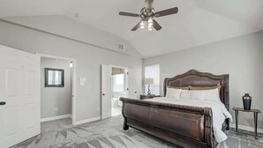 Une chambre avec un grand lit, un ventilateur de plafond et un sol recouvert de moquette.