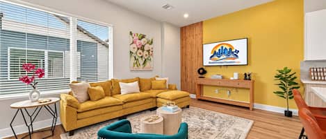 A modern living room with a yellow sofa, a teal armchair, and a wooden coffee table.