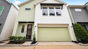 Une maison à deux étages avec un garage, une porte d’entrée et un petit porche.