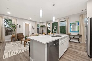 A modern kitchen with a central island, stainless steel appliances, and a green accent wall. - Tropical Jungle Home Escape & Retreat (Houston)