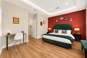 Een slaapkamer met een bed, bureau, stoel en een rode accentmuur.