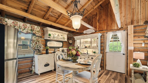 Une cuisine rustique avec des poutres en bois, une table à manger avec des chaises, un plan de travail et un panneau indiquant l’emplacement de la cuisine et du bistro.
