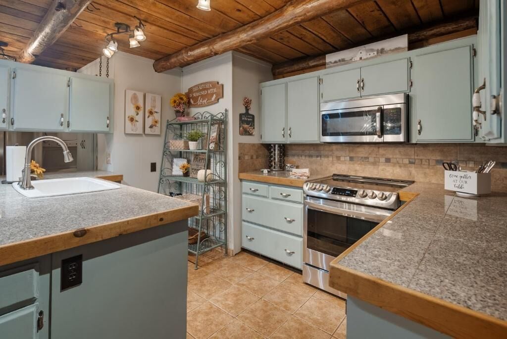 Una cocina con armarios azul claro, estufa de acero inoxidable y encimera de granito.