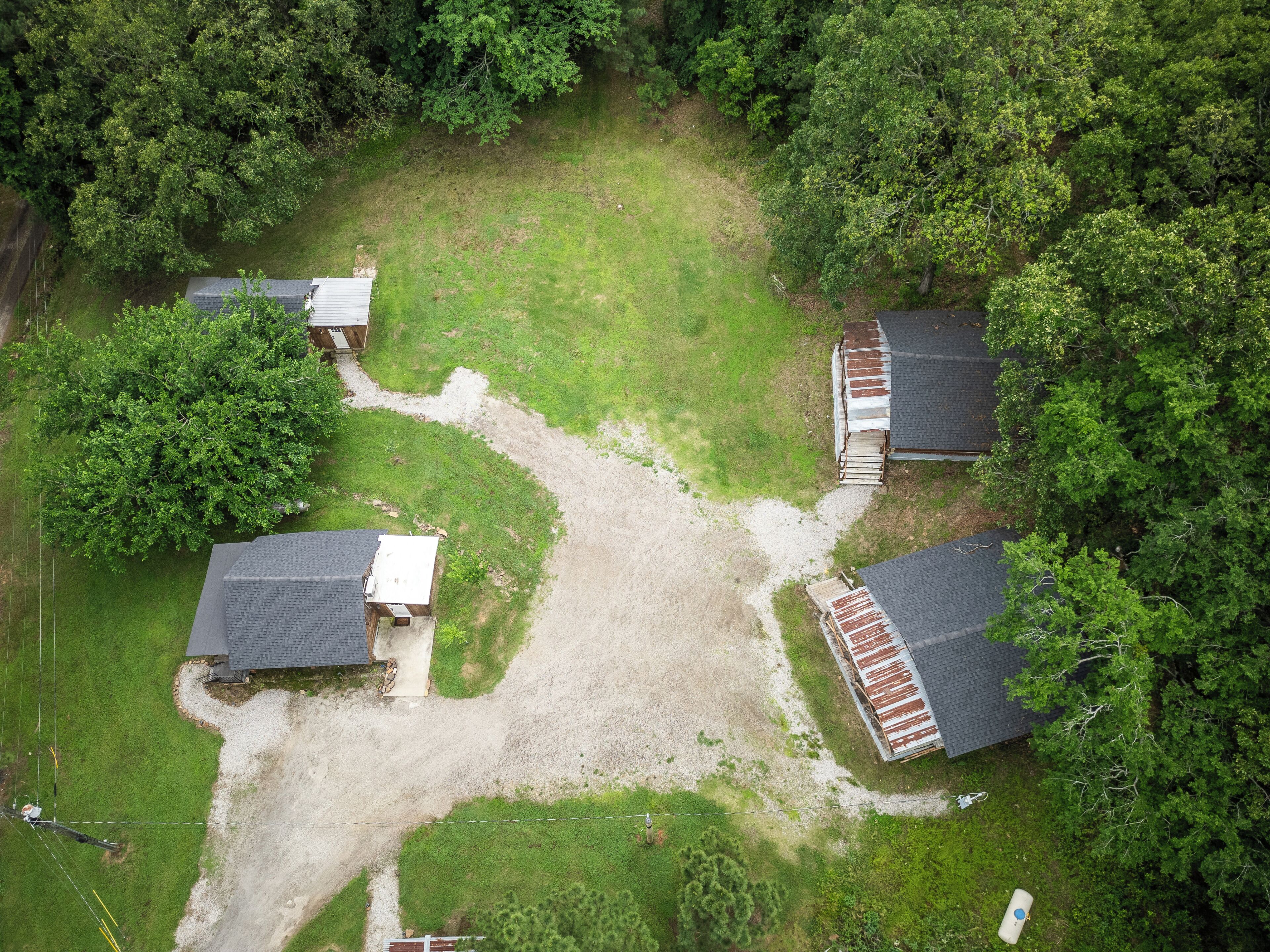 Luchtbeeld van een woonwijk met meerdere huizen, een grindpad in het midden en veel groen eromheen.