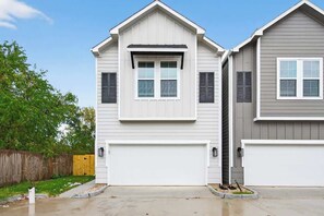 Two single-story houses with attached garages, a wooden fence, and a clear sky.