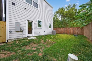 A residential house with a white exterior, a wooden fence, and a grassy yard.