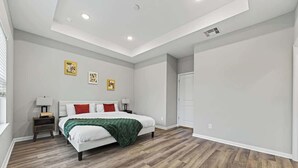 Un dormitorio con cama, mesitas de noche y obras de arte en la pared.
