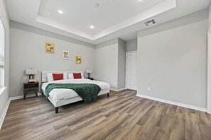 A bedroom with a bed, nightstands, and artwork on the wall.