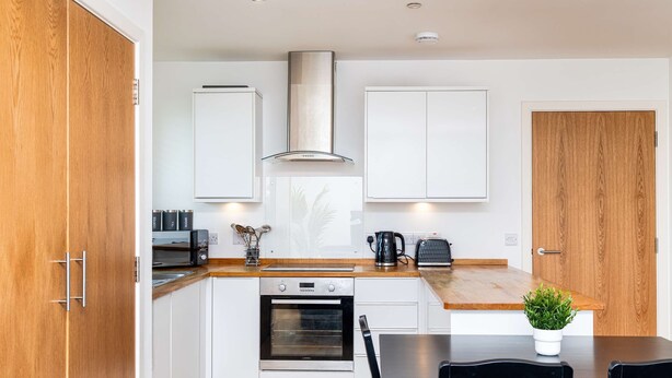 A modern kitchen with white cabinets, a stainless steel oven, and a wooden door. - Spacious 2BR Ground Floor Sleeps 5 Near Peterhead Harbour FREE Parking Fast WiFi (Aberdeenshire)
