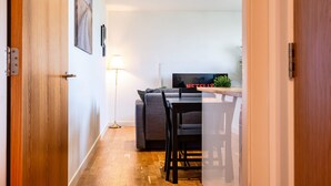 A modern interior with a wooden door, a dining area with a table and chairs, a sofa, a TV displaying 'NETFLIX,' and a floor lamp. - Spacious 2BR Ground Floor Sleeps 5 Near Peterhead Harbour FREE Parking Fast WiFi (Aberdeenshire)