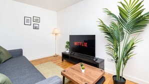 A living room with a sofa, a coffee table, a TV, a lamp, and a potted plant. - Spacious 2BR Ground Floor Sleeps 5 Near Peterhead Harbour FREE Parking Fast WiFi (Aberdeenshire)