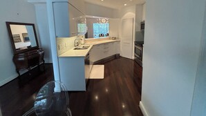 A modern kitchen with white cabinetry, a stainless steel sink, and a built-in oven. - Spacious 4-bedroom apartment At IMG Academy (Bradenton)