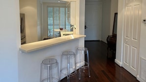 A modern bathroom with a large mirror, a countertop, and three clear stools. - Spacious 4-bedroom apartment At IMG Academy (Bradenton)