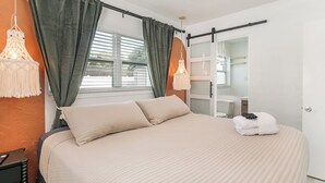 A bedroom with a bed, curtains, a hanging light fixture, a ceiling fan, and a view of the outside. - Beachside 3BR w/ New Hot Tub & Huge Backyard (Largo)