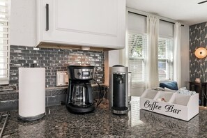 A kitchen with a coffee maker, a paper towel dispenser, and a coffee bar. - Beachside 3BR w/ New Hot Tub & Huge Backyard (Largo)