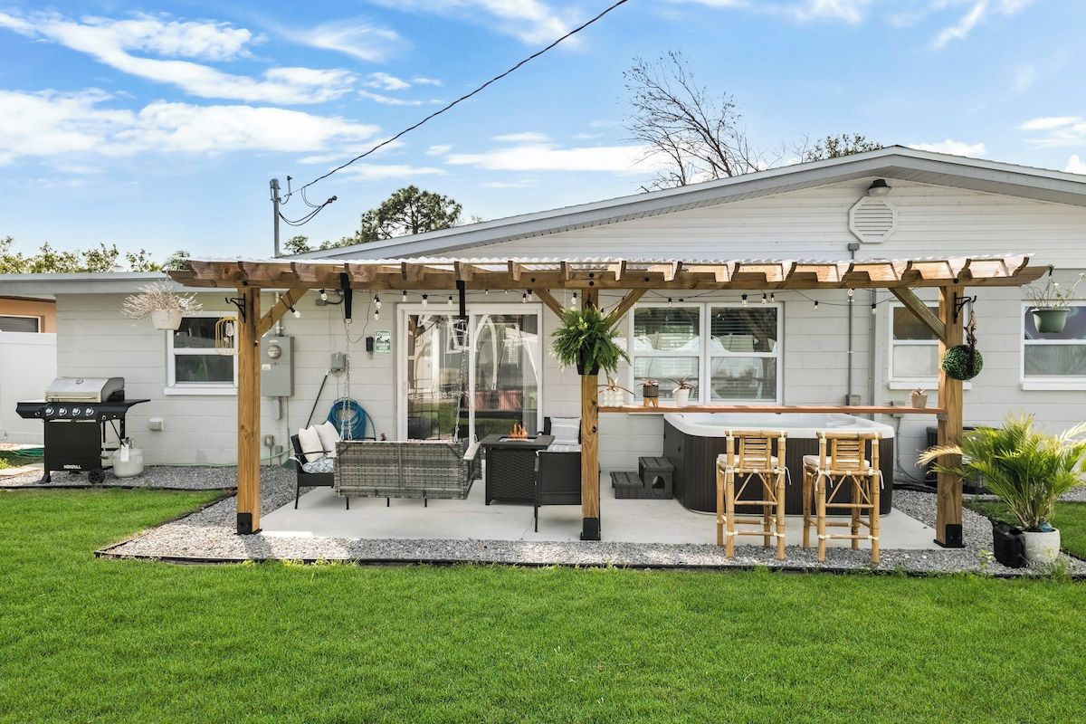 A residential property with a covered patio, outdoor seating, and a barbecue grill.