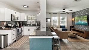 A modern kitchen with white cabinets, a central island, and stainless steel appliances. - Beachside 3BR w/ New Hot Tub & Huge Backyard (Largo)