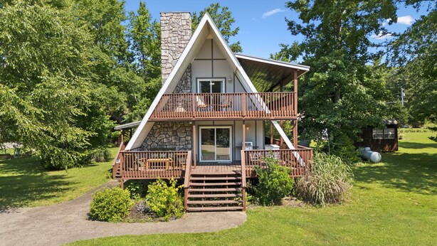 A two-story cabin with a stone chimney, wooden deck, and a small cabin-like structure to the side. - Lakeside Escape (Dover)