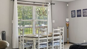 A dining area with a table and chairs, a chandelier, a view through the window, and a paddle on the wall. - Lakeside Escape (Dover)