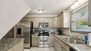 A kitchen with stainless steel appliances, granite countertops, and a window with blinds. - Lakeside Escape (Dover)