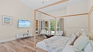 Een slaapkamer met een hemelbed, een televisie, een witte console en uitzicht op de omgeving.