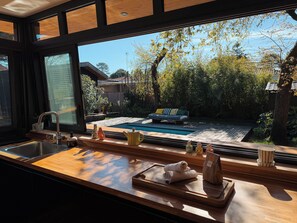 Eine Küche mit großem Fenster, Spüle und Holzarbeitsplatte.
