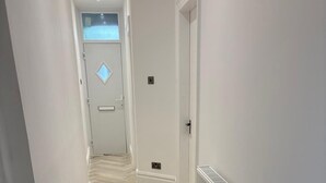 A hallway with a herringbone floor pattern, white walls, and a radiator on the right. - Coastal Retreat, Rhos-on-Sea, 1-Min Walk to Beach (Rhos on Sea)