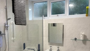 A modern bathroom with a glass shower enclosure, a white sink, a toilet, and a glass shelf with toiletries. - Coastal Retreat, Rhos-on-Sea, 1-Min Walk to Beach (Rhos on Sea)