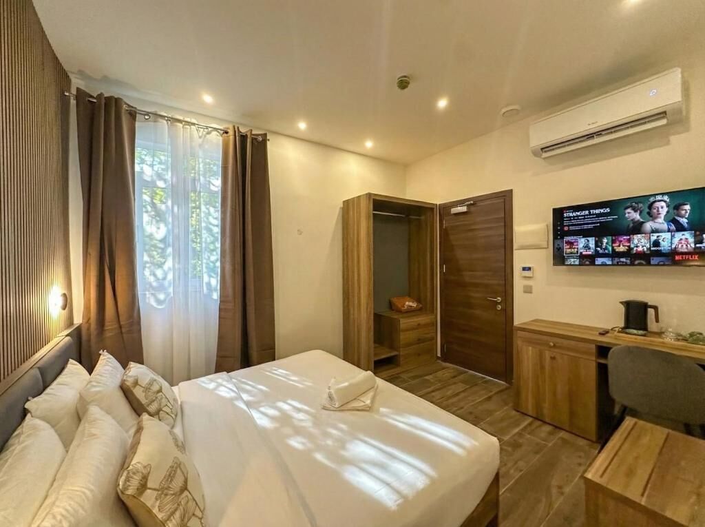 Een hotelkamer met een bed, bureau, televisie en kledingkast.