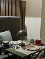 Una mesa de comedor ordenada con una lámpara, platos, vasos y cubiertos.