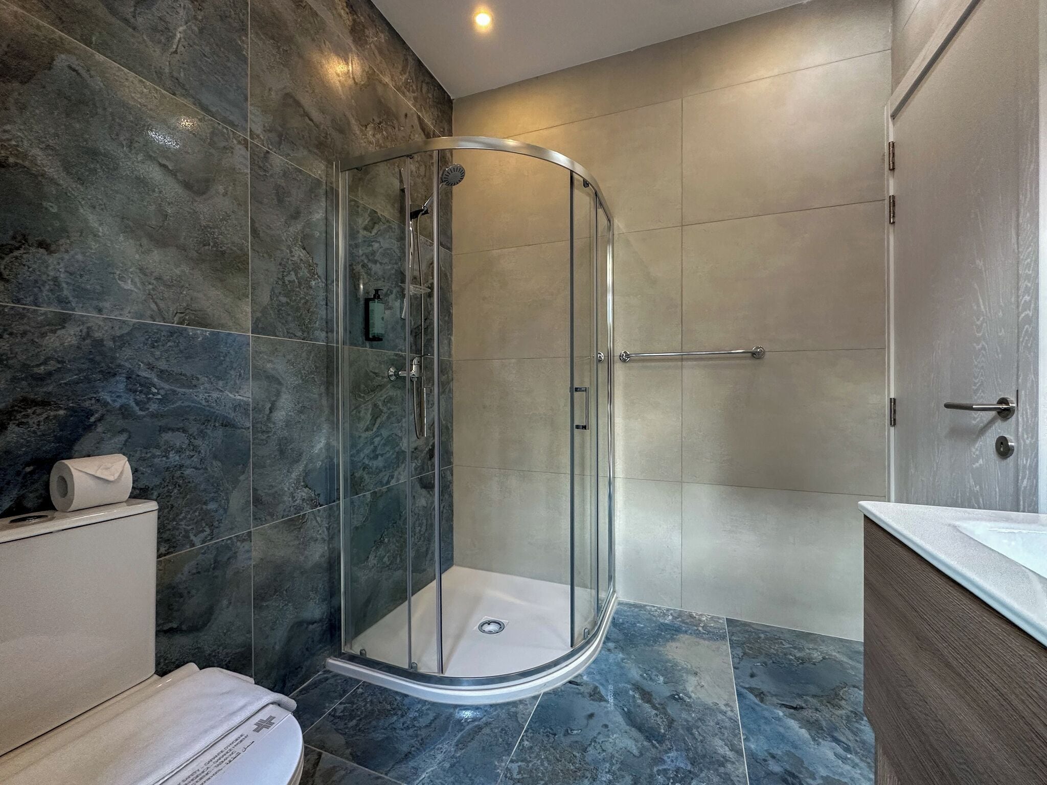 Un baño moderno con ducha de vidrio, inodoro y lavamanos.