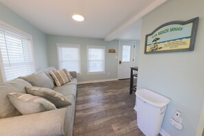 Un salon avec un canapé, une poubelle et un panneau décoratif au mur.