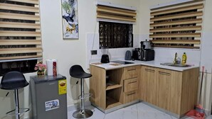 A compact kitchen with a refrigerator, a coffee maker, and a sink. - Savvy Studio Apt@RealShala Galaxy-School-Adjiringanor (Ashaley Botwe)