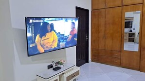 A television mounted on a wall, a wooden wardrobe, and a tiled floor. - Savvy Studio Apt@RealShala Galaxy-School-Adjiringanor (Ashaley Botwe)
