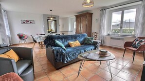 Un salon avec un canapé, une table basse et, au fond, un coin repas.