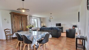 Un espace repas comprenant une table et des chaises, un canapé, un téléviseur et un meuble.
