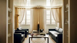 Ein Wohnzimmer mit zwei schwarzen Ledersofas, einem Couchtisch und einem Bücherregal mit Gläsern.
