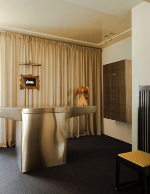 A hotel room with a minibar, a wooden sculpture, a coat rack, and a black chair. - Mont Thabor Vendôme Residence (Paris)