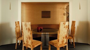 Ein Essbereich mit einem runden Tisch, vier Stühlen, einer Blumenvase und einer Wandleuchte.