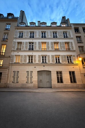 A multi-story building with a symmetrical facade, large central doors, and multiple windows with shutters. - Mont Thabor Vendôme Residence (Paris)