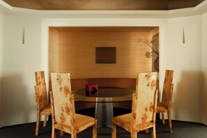 A dining area with a round table, four chairs, a vase with flowers, and a wall-mounted light fixture. - Mont Thabor Vendôme Residence (Paris)