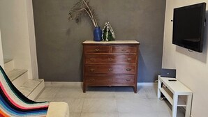 Huoneessa on sohva, puinen lipasto, taulutelevisio ja kuviollinen matto.