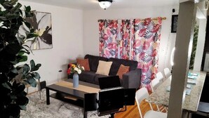 Un salon avec un canapé, une table basse et une plante.