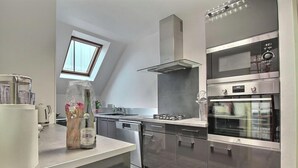 A modern kitchen with a built-in oven, a gas stove, and a skylight. - Ty Bihan - PLEUMEUR GAUTIER (PLEUMEUR GAUTIER)
