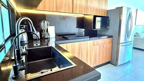 A modern kitchen with stainless steel appliances, wooden cabinets, and a built-in microwave. - Resort-Style Condo- Pool, Patio, Playground + Palapa Lounge (Aldea Hortus)