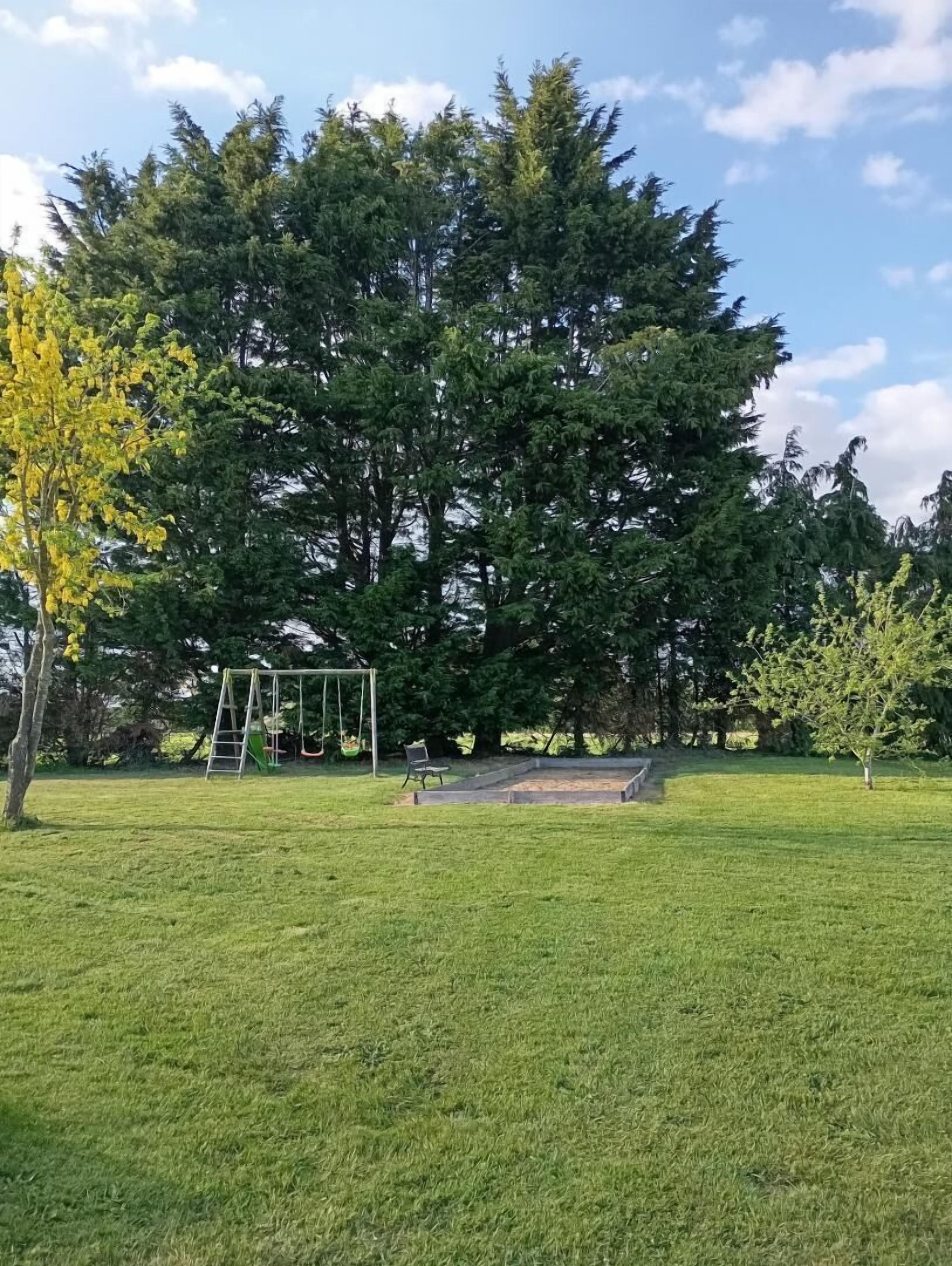 A grassy park with a swing set and a bench.