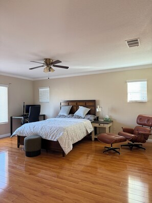 Une chambre avec un lit, un bureau, une chaise, un ventilateur de plafond et une fenêtre.