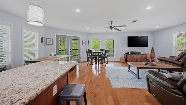 A spacious living area with a kitchen, dining table, and a TV. - Answered Prayers Main House-Step out to a peaceful morning or star gaze at night (Kingston)