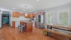 A kitchen with wooden cabinets, stainless steel appliances, a central island, and a dining area with a bench. - Answered Prayers Main House-Step out to a peaceful morning or star gaze at night (Kingston)