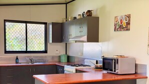 Eine moderne Küche mit einer zentralen Kochinsel, Barhocker, einer Mikrowelle und einem Fenster mit Blick.